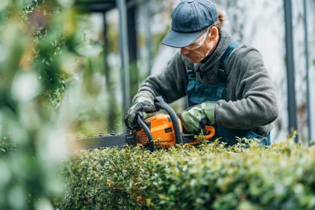 Jardinero profesional podando un seto en un jardín residencial